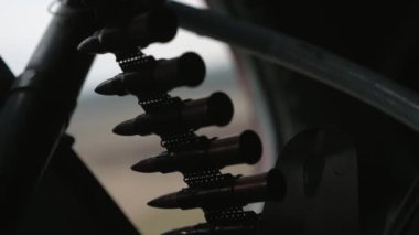 İlkbahar havasında uçan helikoptere yerleştirilmiş modern bir makineli tüfek için mermilerle dolu bir kartuş bandının profesyonel yakın plan helikopterine yerleştirilmiş mermilerle dolu çağdaş bir makineli tüfek. Cesur ve tehditkar görünüyor..