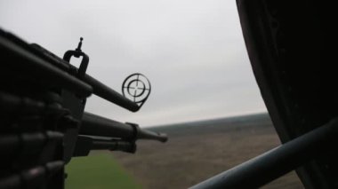Yuvarlak görüşlü büyük makineli tüfekle helikopter objeleri hedef alınır. Kartuş bantlı modern bir makineli tüfeğin etkileyici görüntüsü ve baharda bulutlu bir havada helikopterde uçan nesnelere yerleştirilmiş kara cisimlerini hedef alan yuvarlak bir görüş açısı.