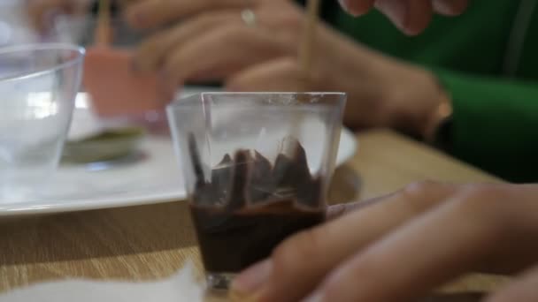 専門家は 研究室で新しい素晴らしい味を得るためにスパイスと黒チョコレートをミックス小さな木製の棒を持つ科学者の陽気な閉鎖研究室で液体チョコレートと一緒にシースループラスチックフラスコに回転 — ストック動画