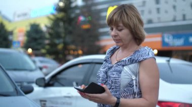 Yavaş çekimde şehrin bir sokağında telefonuyla arayan sarışın bir kadın. Hafif elbiseli, zeki bir sarışının, şehrin işlek bir sokağındaki akıllı telefonunu yavaş çekimde araması heyecan verici. Orada ağaçlar ve arabalar görülür..