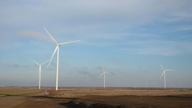 Yazın bozkırda yavaşça dönen dört elektrikli rüzgar değirmeni. Güneşli bir yaz gününde uzun bıçakları yavaşça dönen dört elektrikli rüzgar kulesi. Neşeli ve profesyonel görünüyor.