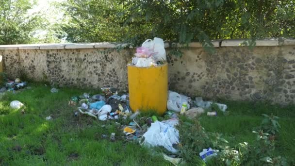 공원에 콘크리트 쓰레기통에는 플라스틱 쓰레기가 노란색둥근 콘크리트 쓰레기통 지역의 울타리에 — 비디오