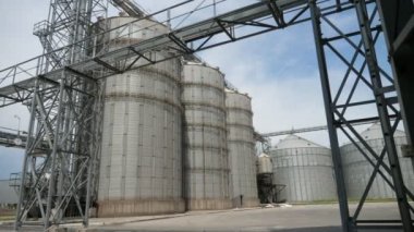 Sonbaharda üç yüksek tank ve iki orta boy soya yağı deposu. Güz mevsiminde gri bir günde birçok metalik yapıya sahip çağdaş bir soya yağı fabrikasının üç yüksek ve iki orta sarnıç manzarası.