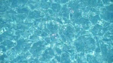 Köpüklü sular, yazın açık mavi dalgalarla dalgalanan bir yüzme havuzunda dalgalanır. Güneşin neşe saçan ışıklarıyla parlayan ve dalgalanan suların güzel manzarası. Yavaş çekimde modern bir havuzun açık mavi dalgalarında salınır..