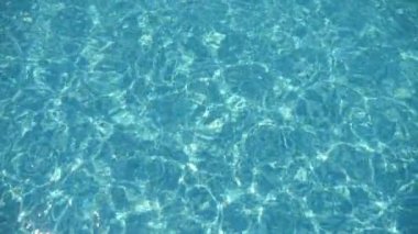 Sihirli sular turkuaz bir havuzda ışıkla oynuyor güneşli bir ağ oluşturuyor modern yüzme havuzunda yavaşça sallanan açık mavi dalgaların muhteşem görüntüsü dinlendirici desenler oluşturuyor ve güneş ışınlarından ağ oluşturuyor..