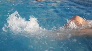 Mavi sularda bisiklet hareketleri yapan kadın ayakları ağır çekimde yüzme havuzunun damlacıklarını yavaş çekimde kaldırarak ve sıçratarak mavi sularda bisiklet hareketleri yapan kadın bacaklarının neşeli görüntüsü. Neşeli ve güzel görünüyor..