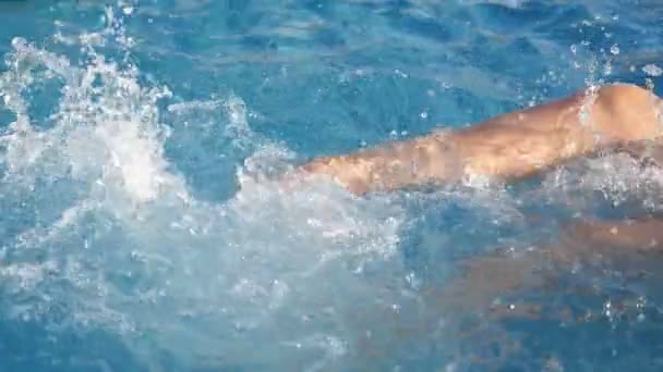 在游泳池的蓝色水中做自行车运动的女性腿在蓝色的水里做自行车运动的女性腿在蓝色的水里做自行车运动的原始画面 缓慢地喷射和飞溅着游泳池的水滴 看起来很开心 — 图库视频影像