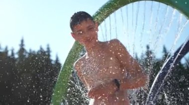 Karpatlar 'da yaz aylarında, yuvarlak bir duşta dans eden neşeli bir çocuk. Kısa saçlı, kısa saçlı, dans eden bir çocuk. Güneşli bir günde, dağlarda neşe saçan su akıntıları eşliğinde, yeşil bir çember içinde dans ediyor.