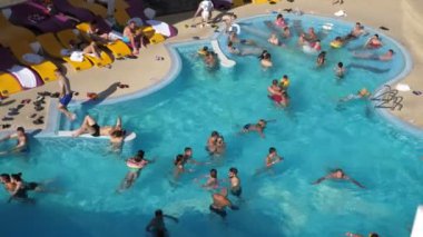 Bukovel, Ukrayna - 22 Ağustos 2021: Yüzme havuzlu Bukovel Dağı 'nın muhteşem manzarası ve birçok insan güverte sandalyelerinde uzanıyor, yüzüyor, suda sarılıyor ve yazın dinleniyor. İyimser görünüyor..