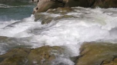 Yazın kayalık ve taştan taşlı şelalenin üzerine dökülen bir dağ nehrinin köpüklü akıntıları, yazın güneşli bir günde Carpathian dağlarında kayalık ve taştan taşlı çağlayandan dökülen bir dağ nehrinin foto-şeffaf akıntılarının yakın çekimi..