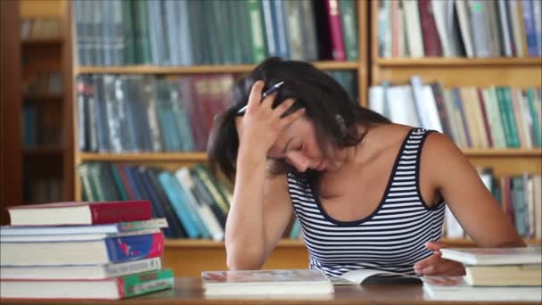 Müde schöne Studentin in der Bibliothek 1 — Stockvideo