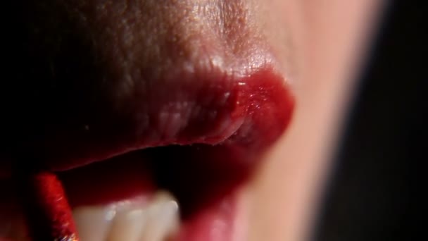 Mujer pinta sus labios con lápiz labial sobre un fondo negro, primer plano 2 — Vídeos de Stock