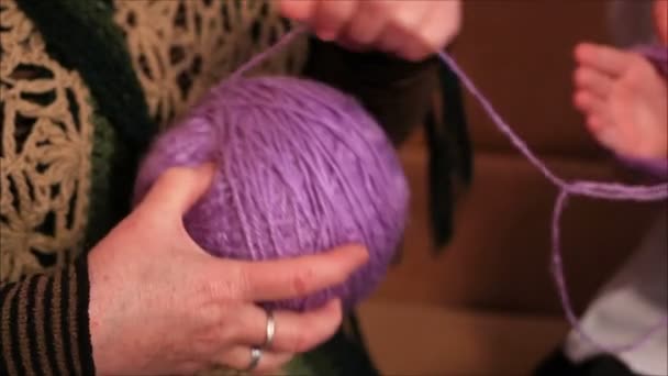 Woman and girl roll up the yarn — Stock Video