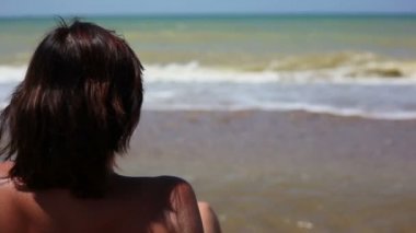 Kumsalda oturan kadın.