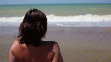 Kumsalda oturan kadın.