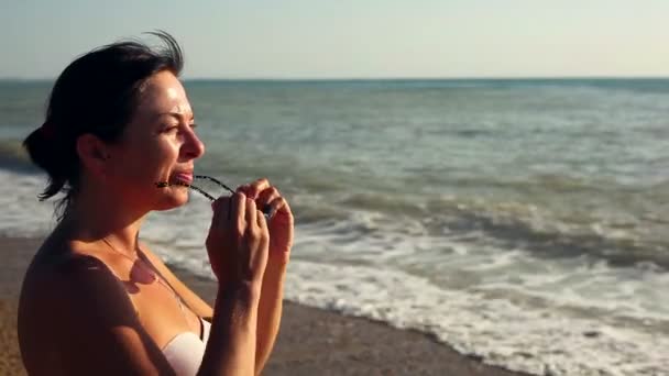 Жінка стоїть на пляжі — стокове відео