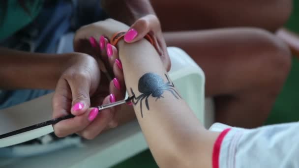 Женщина рисует паука на руке — стоковое видео