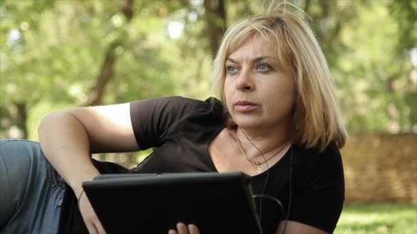 Blondýnka poslouchá hudbu na počítači tablet — Stock video