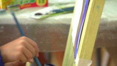 Çocuk bir fırça tuval üzerine çizer.