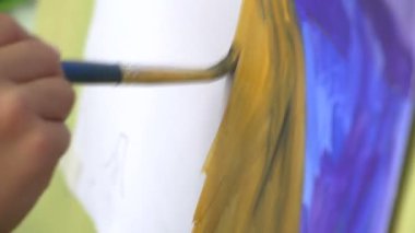 Çocuk bir fırça tuval üzerine çizer.