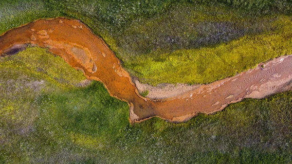 Kırmızı nehir yeşil çayırlarla çevrili.