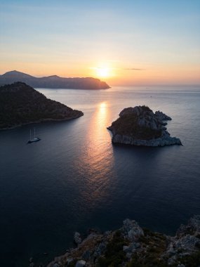 Altın gün batımında Akdeniz adasının gölgesinin havadan görünüşü sakin denizde sıcak bir ışık ile