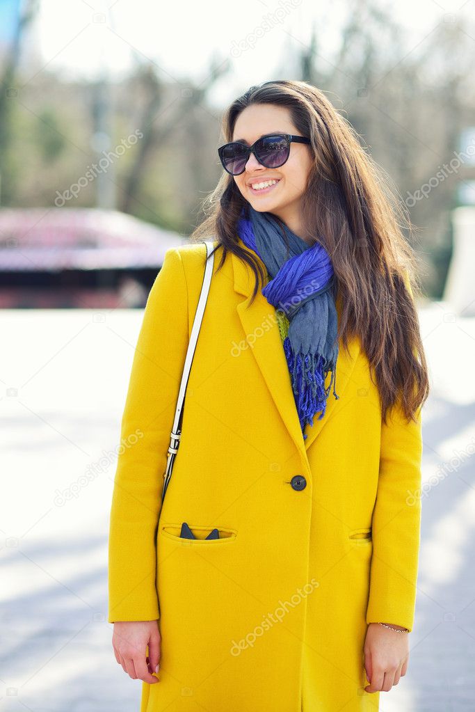 Young smiling brunette woman in a yellow coat and sunglasses, Sp