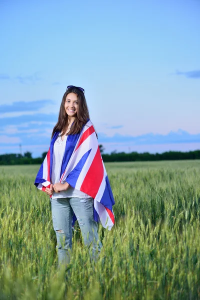 young smiling girl in a field of wheat. Flag of the England
