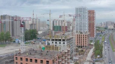 Monolitik bir evin inşaatı, inşaat vinçleri ve işçiler üzerinde İHA uçuşu