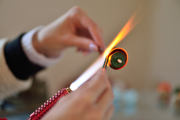 woman's hands with tools for glass melting, the time of producti