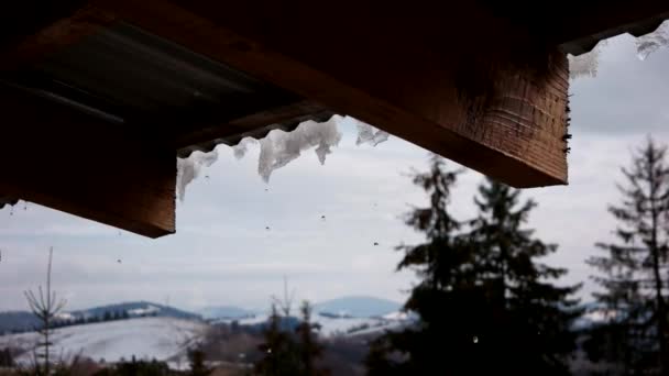 Derretimiento de nieve en el tejado con un fondo de montañas — Vídeo de stock
