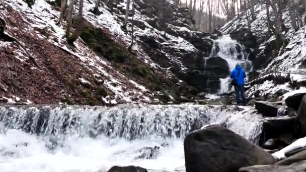 Фотограф, делающий фото зимних водопадов в горах — стоковое видео