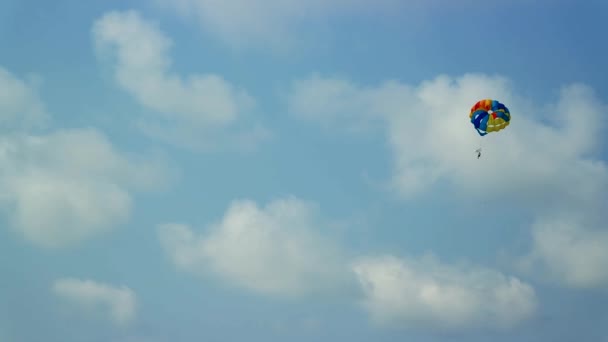 Человек на парашюте, летящем над морем — стоковое видео