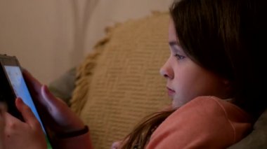 Sevimli kız oturma kanepe ve Tablet ile çalmayı