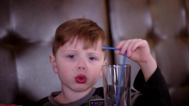 Niño bebiendo jugo y comiendo pizza en la cafetería — Vídeos de Stock