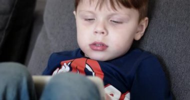 Çocuk çizgi yan görünüm bir Tablet bilgisayarda film izlerken