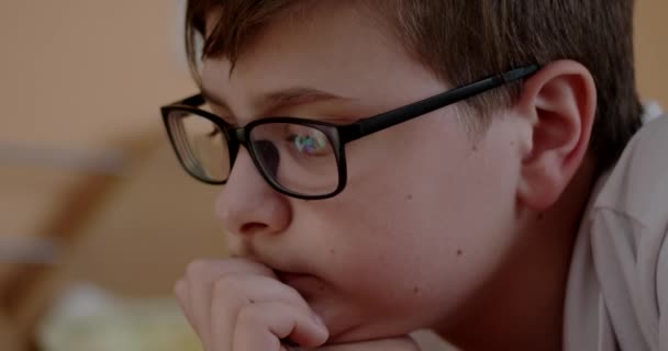 Boy in Glasses Watching Videos on a Tablet Lying on the Bed — Stock Video