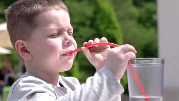 Joven niño bebiendo jugo en café al aire libre — Vídeos de Stock