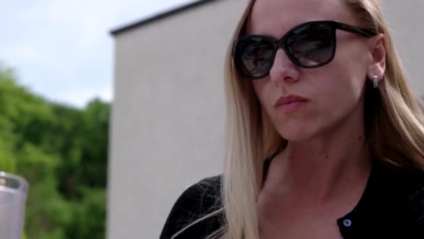 Joven mujer de negocios en gafas de sol en un café al aire libre . — Vídeos de Stock