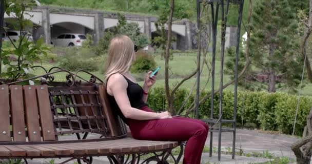 Женщины используют смартфон на скамейке в парке — стоковое видео