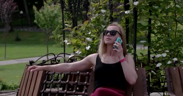 Vrouwen met behulp van smartphone op de Bank in het park — Stockvideo