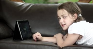 Teras deri kanepede yatan Tablet bilgisayar kullanan kız