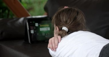 Teras deri kanepede yatan Tablet bilgisayar kullanan kız