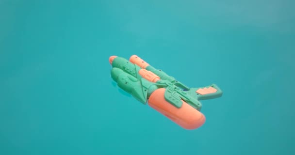 Pistola de agua flotando en una piscina azul Agua — Vídeos de Stock