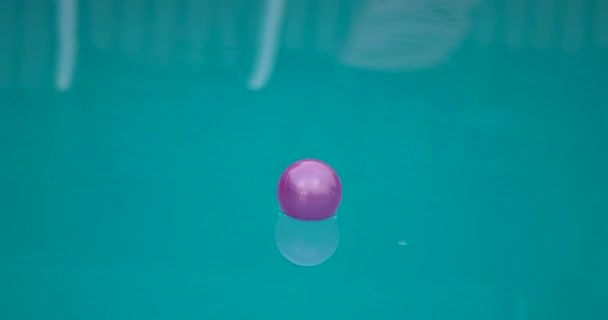 Lila Ball schwimmt auf Wasseroberfläche eines Schwimmbades — Stockvideo
