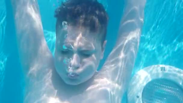 Teen Boy bucea en la piscina azul con los ojos cerrados y hacer algunas burbujas. Moción lenta — Vídeos de Stock