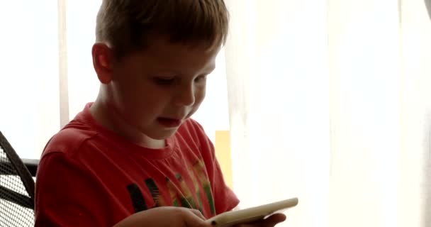 Kind met behulp van de Touchpad tijdens het spelen van videospellen zitten in de stoel van het Bureau — Stockvideo