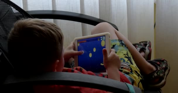 Criança usando Touchpad enquanto joga videogames sentada na cadeira do escritório — Vídeo de Stock