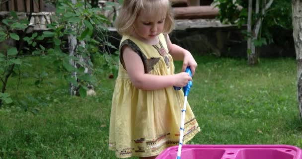 Милая девочка играет со своим набором игрушек для рыбалки на открытом воздухе — стоковое видео