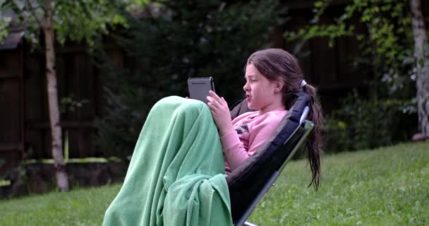 Little Girl Using Touchpad on Chair Outdoor — Stock Video